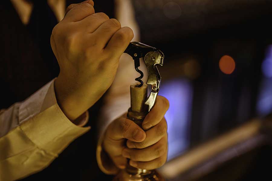 Opening wine bottle with a corkscrew.